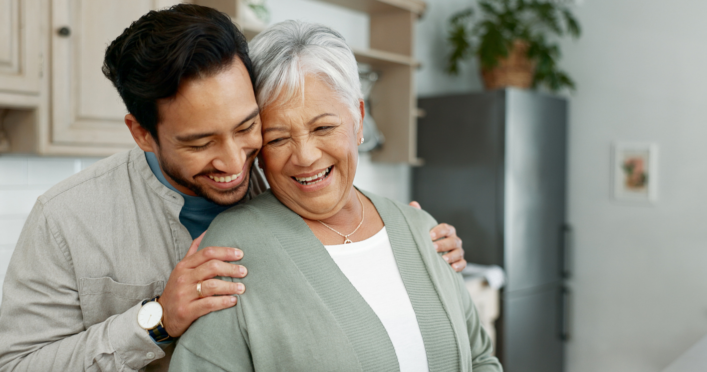 Home, senior mother and son with hug for care, comfort and assurance with bonding together in kitchen. Happy people, elderly mom and man with embrace for mothers day, support and expression of love memory care